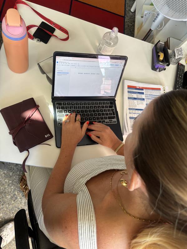 Overhead shot of Jenn working at her laptop with notebooks
